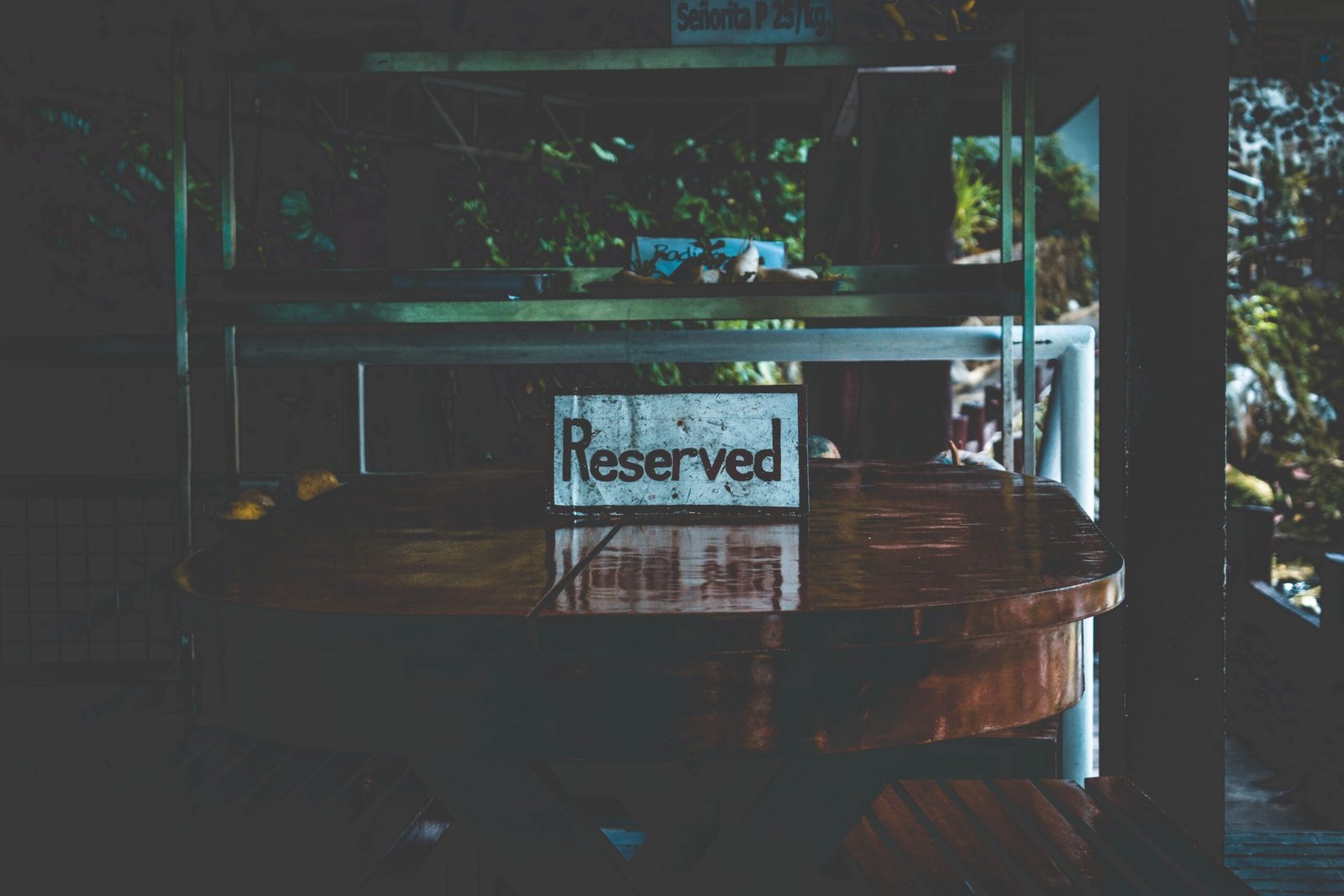 A dimly lit table with a reserved sign, set in an outdoor environment creating a moody atmosphere.